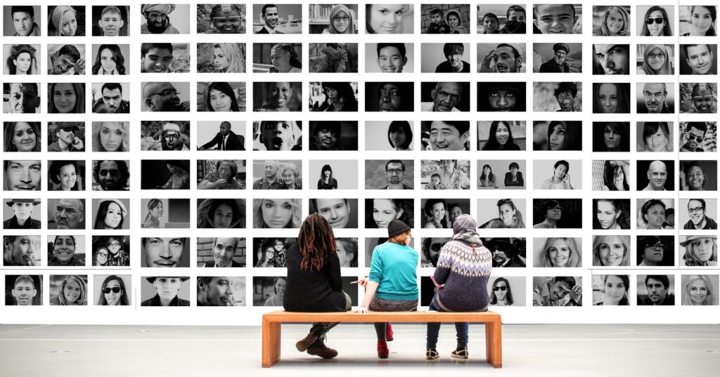 people viewing a gallery wall of portraits