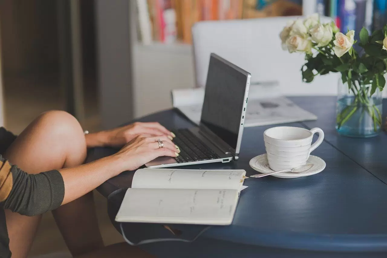 woman writing on laptop and notebook